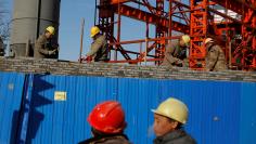 FILE PHOTO: Workers lay bricks to build a wall around a construction site in Beijing, China, December 15, 2017.  REUTERS/Thomas Peter/File Photo      