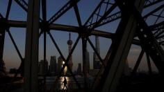 A man walks on a bridge in front of the financial district of Pudong in Shanghai, China, December 8, 2017. REUTERS/Aly Song 