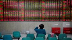 An investor looks at an electronic board showing stock information at a brokerage house in Shanghai, China November 24, 2017. REUTERS/Aly Song