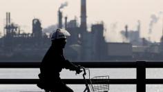 FILE PHOTO: A worker cycles near a factory at the Keihin industrial zone in Kawasaki, Japan, November 15, 2017.  REUTERS/Toru Hanai/File Photo 